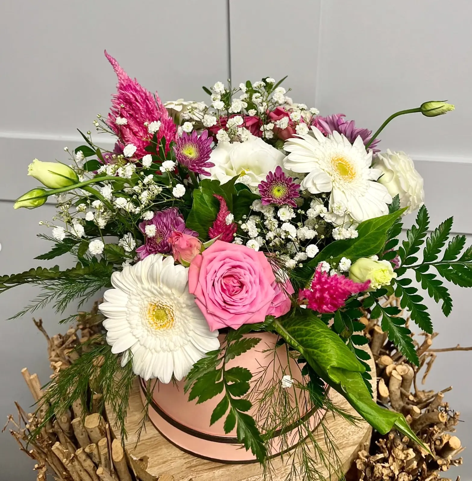 A blush pink hat box arrangement of white gerberas, pink roses and gypsophila made by the Leaf + Bean florist