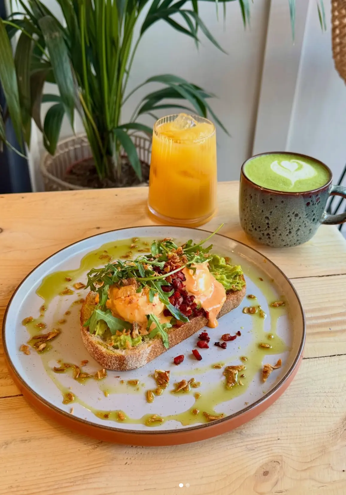 Mexican benedict on sourdough with chorizo and sriracha hollandaise beside a matcha latte at Leaf + Bean